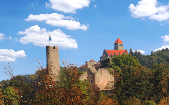 Burgruine Windeck und Wachenburg im Grünen vor strahlend blauem Himmel mit weißen Wolken