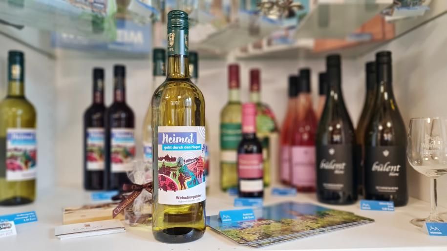 Weinflasche mit Weißwein im Hintergrund sieht man unscharf weitere Flaschen