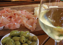 Oliven und roher Schinken sowie ein Glas Weißwein