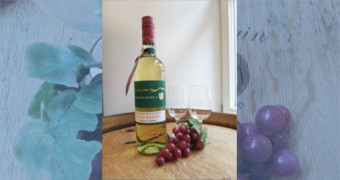Flasche Roter Riesling mit Weintrauben auf einem Holzfass