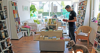 Regale mit Büchern, ein Mann mit Hund der im Buch liest
