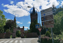 Autowegweiser vor der Silhouette des Berckheimer Schlosses mit strahlend blauem Himmel.