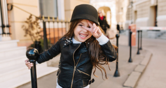 Mädchen mit schwarzer Jacke macht das Peace-Zeichen