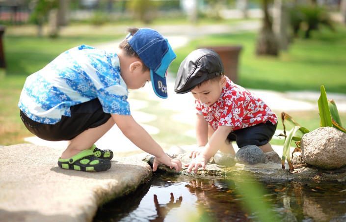 zwei kleine Jungen spielen an einem Bachlauf