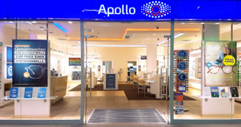 Über dem Eingang ein blaues Band mit Apollo schriftzug, Blick ins Innere der Filiale