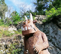Eine Holzstatue des Grüffelo vor einer Felswand
