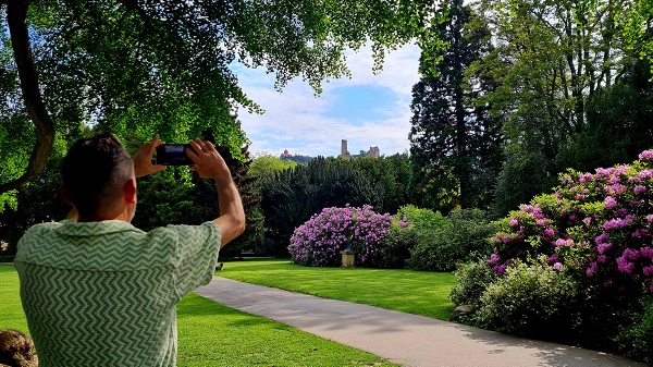 Ein Mann steht vor der Kulisse des Schlossparks und fotografiert