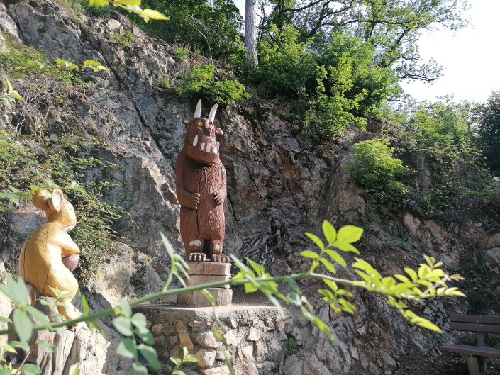 Grüffelo-Statue aus Holz vor Felswand