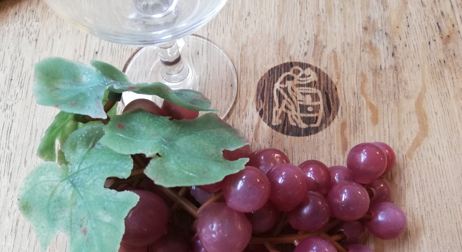Weinglas mit roten Weintrauben auf einem Holzfass